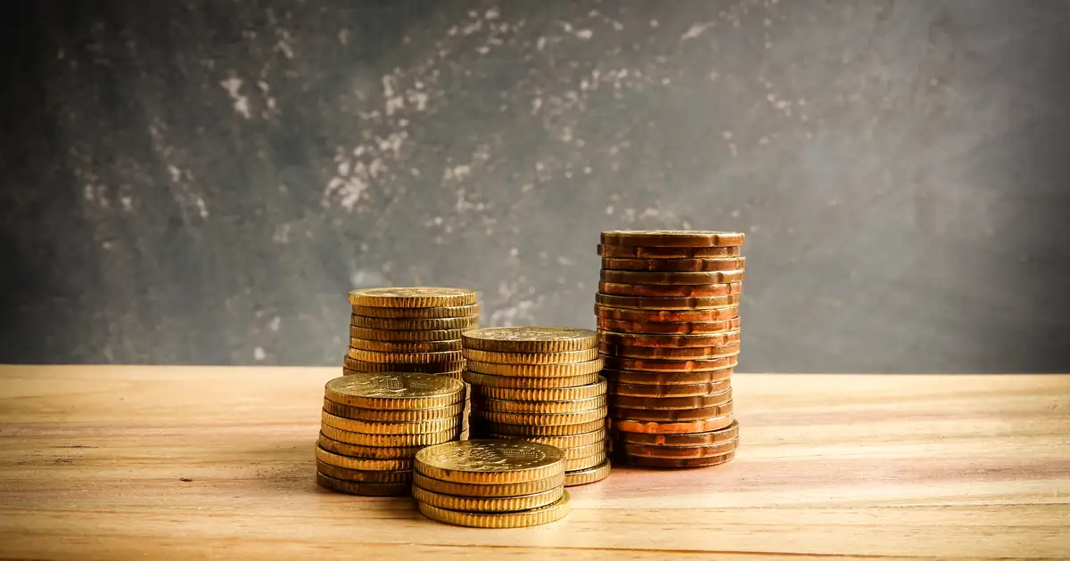 Moedas antigas e calculadora simbolizando custos reais da estruturação de holding versus custo de adiar