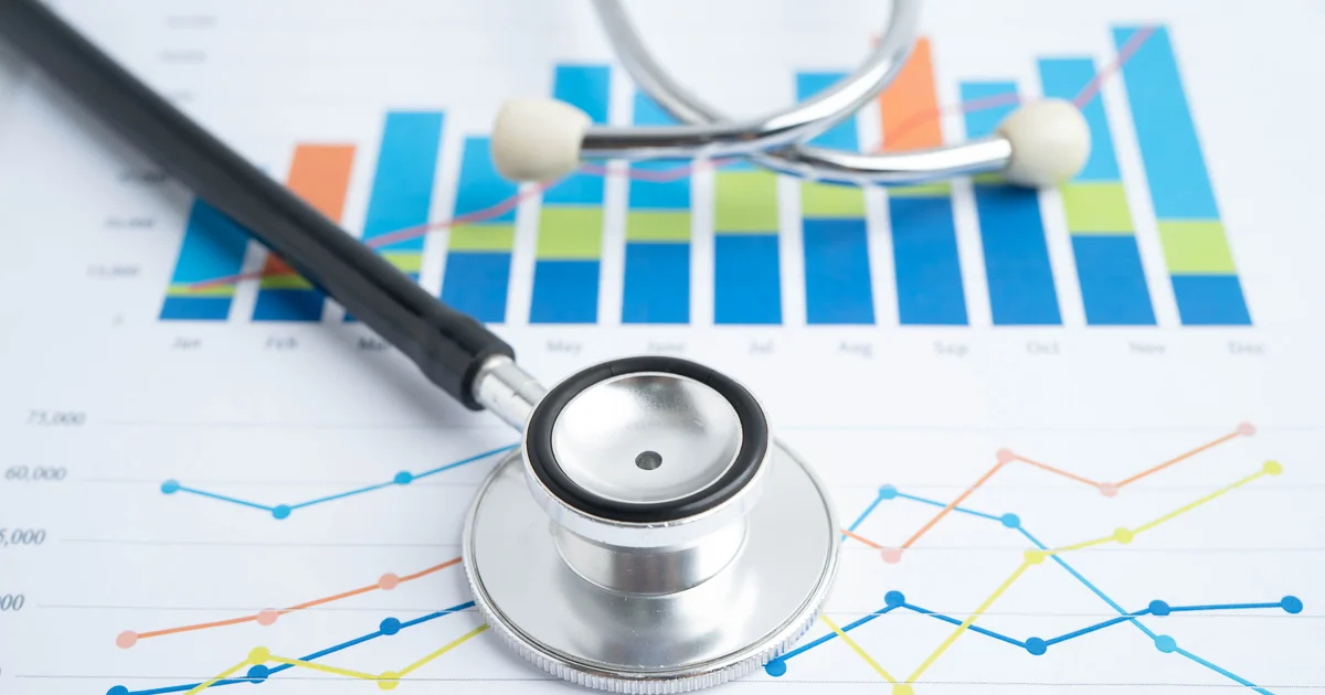 Estetoscópio sobre gráficos comparativos mensais representando os 4 regimes tributários para PJ médica em 2026